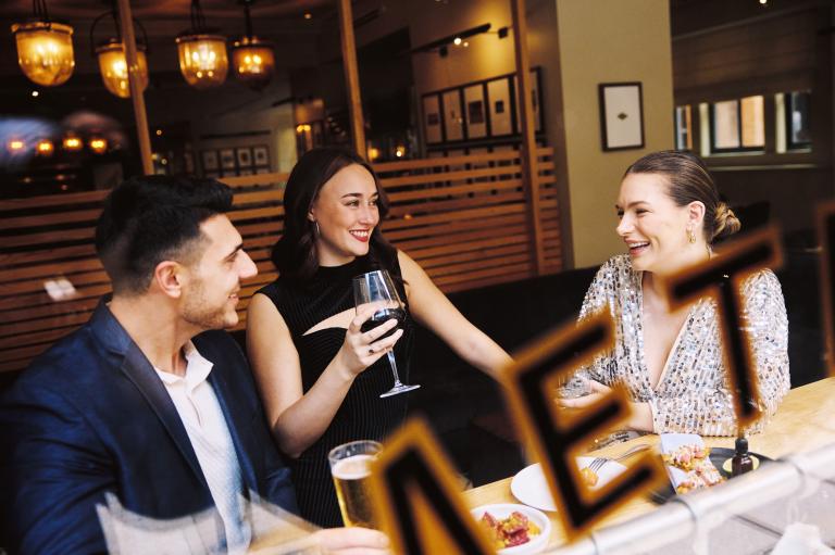 two women and a man having drinks